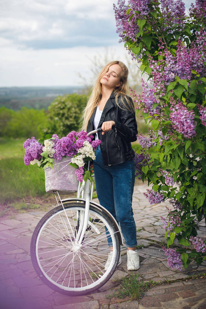 Meisje in een leren jas in de buurt van witte fiets - Foto, afbeelding