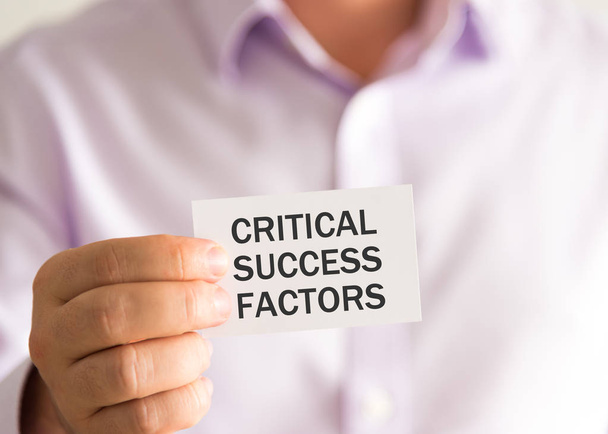 Бізнесмен тримає карту з текстом CRITICAL SUCCESS FACTORS
 - Фото, зображення