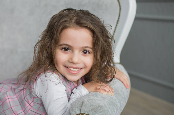 Smiling pretty little girl on a grey sofa - Fotoğraf, Görsel