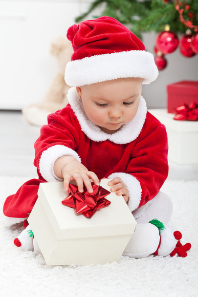 Baby girl in santa outfit opening a present - Фото, зображення