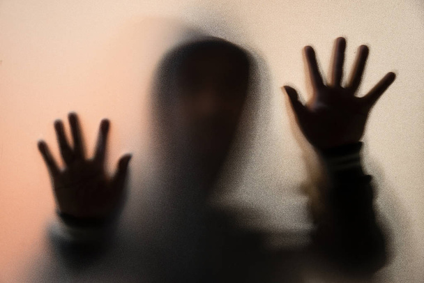 Θόλωσης σκιάς του ανθρώπου τρόμου σε μπουφάν με κουκούλα. Στα χέρια το ποτήρι - Φωτογραφία, εικόνα