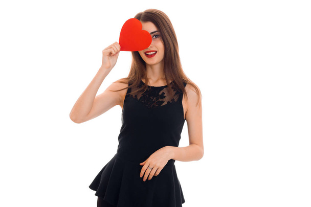 a young girl in a black dress holding a postcard sweetheart near eyes - Foto, imagen
