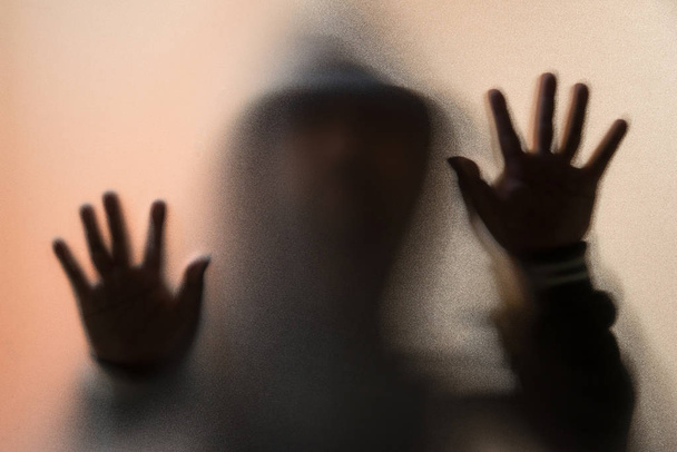 Θόλωσης σκιάς του ανθρώπου τρόμου σε μπουφάν με κουκούλα. Στα χέρια το ποτήρι - Φωτογραφία, εικόνα
