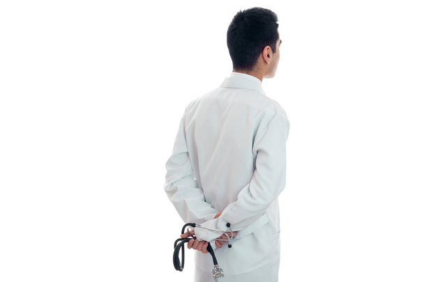 lääkäri valkoisessa puvussa seisoo katsoen taaksepäin ja pitäen stetoskooppia eristettynä valkoisella pohjalla
 - Valokuva, kuva