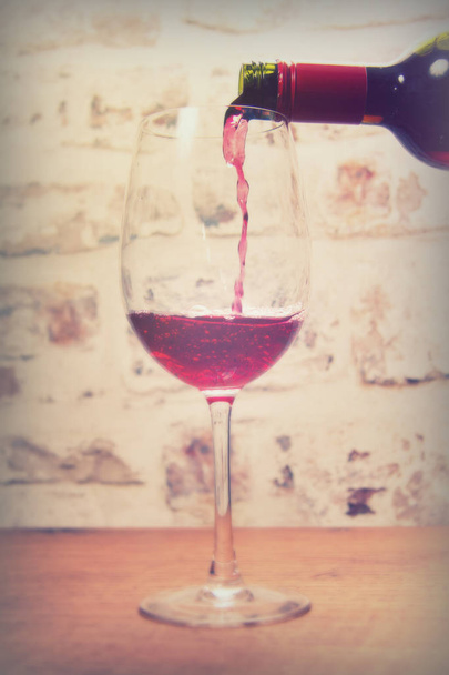 Copa de vino tinto con cuerpo que se vierte
 - Foto, imagen