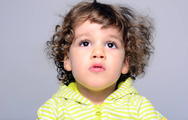 Portrait of a beautiful boy with long curly hair. Toddler looking surprised and playing  - Foto, Imagen