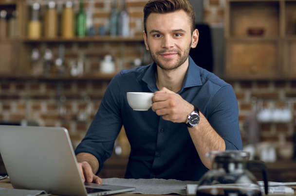 Mann trinkt Kaffee und benutzt Laptop - Foto, Bild