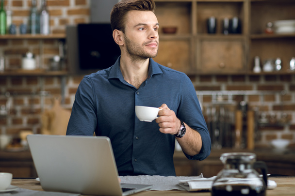 Mann trinkt Kaffee und benutzt Laptop - Foto, Bild