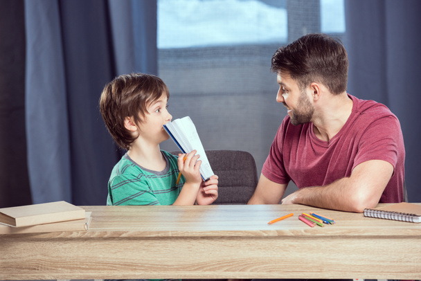 батько допомагає синові робити домашнє завдання
  - Фото, зображення