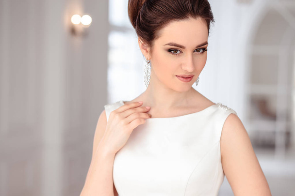 close-up portrait of beautiful brunette bride with elegant hairstyle and makeup wearing long luxury wedding dress - Photo, Image