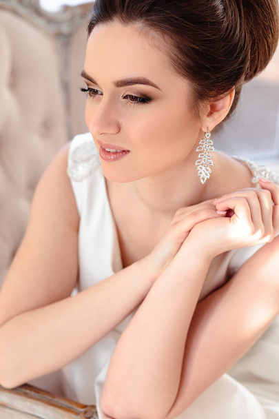 close-up portrait of beautiful brunette bride with elegant hairstyle and makeup wearing long luxury wedding dress - Fotografie, Obrázek