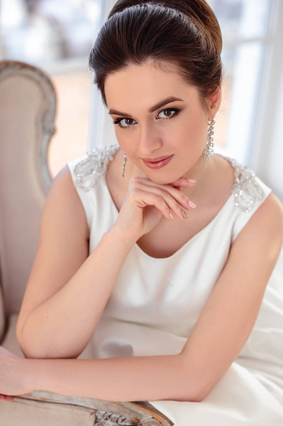 close-up portrait of beautiful brunette bride with elegant hairstyle and makeup wearing long luxury wedding dress - Foto, Imagen