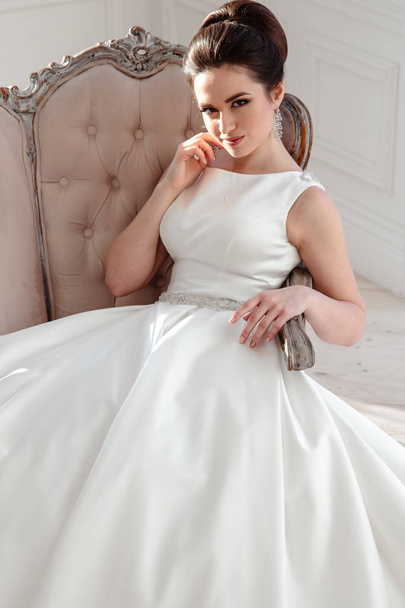 portrait of beautiful brunette bride with elegant hairstyle and makeup wearing long luxury wedding dress - Foto, afbeelding