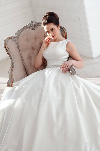 portrait of beautiful brunette bride with elegant hairstyle and makeup wearing long luxury wedding dress - Фото, изображение