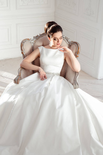 portrait of beautiful brunette bride with elegant hairstyle and makeup wearing long luxury wedding dress - 写真・画像