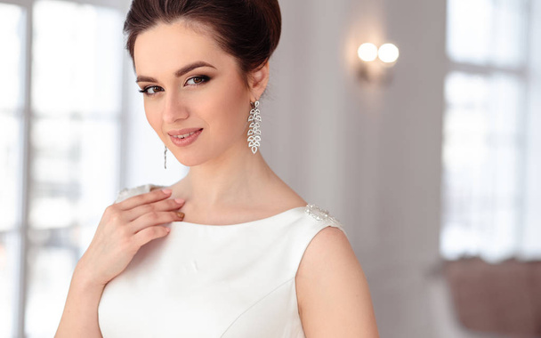 close-up portrait of beautiful brunette bride with elegant hairstyle and makeup wearing long luxury wedding dress - Foto, Imagem