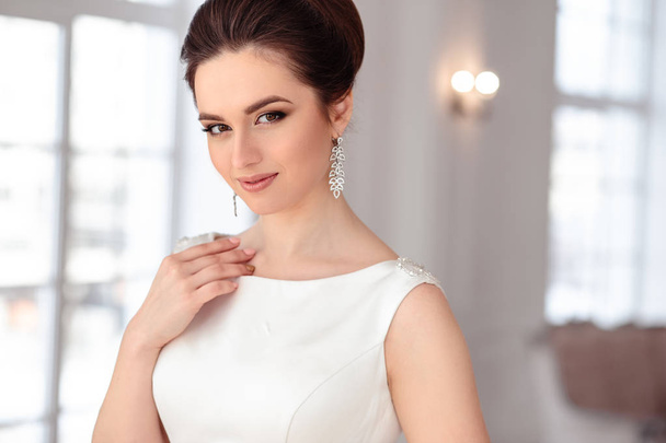 close-up portrait of beautiful brunette bride with elegant hairstyle and makeup wearing long luxury wedding dress - 写真・画像