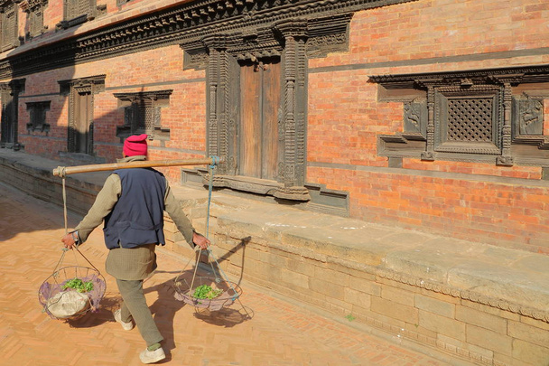 Bhaktapur, Nepal: Een plaatselijke verkoper uitvoering van plantaardige in manden op Durbar Square  - Foto, afbeelding