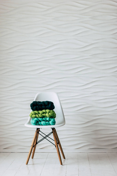 Πολύχρωμο πλεκτό μερινός μαλλί κασκόλ σε λευκή καρέκλα - Φωτογραφία, εικόνα