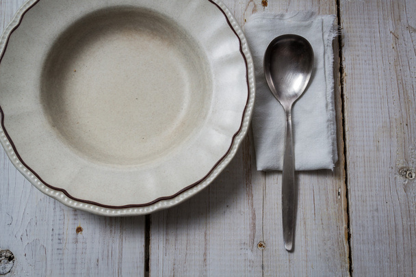 Old empty plate and spoon on wooden table - Fotoğraf, Görsel