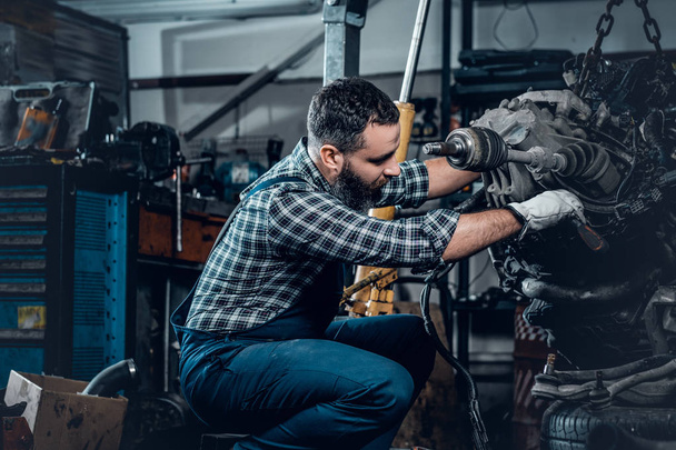 bärtiger Mechaniker repariert Motor eines Autos - Foto, Bild