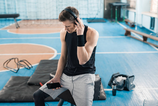 Αθλητικός τύπος στα ακουστικά με έξυπνο κινητό τηλέφωνο - Φωτογραφία, εικόνα