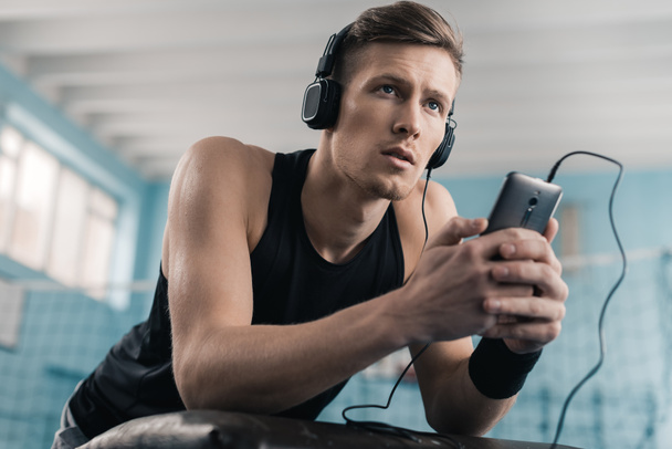 Αθλητικός τύπος στα ακουστικά με έξυπνο κινητό τηλέφωνο - Φωτογραφία, εικόνα