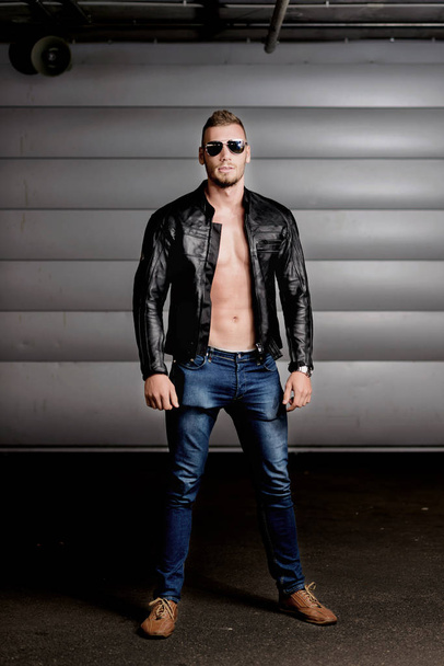 Portrait in full-length white athletic men in a black leather jacket and dark glasses.Toning - Foto, afbeelding