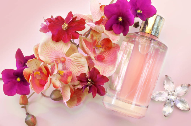 пляшка жіночих парфумів на рожевому фоні
 - Фото, зображення
