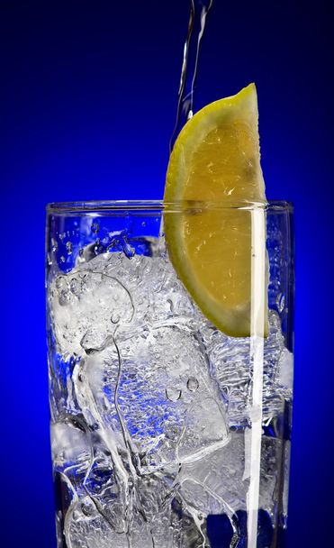 Vista da vicino del bicchiere tonico ghiacciato con limone sul retro blu
 - Foto, immagini