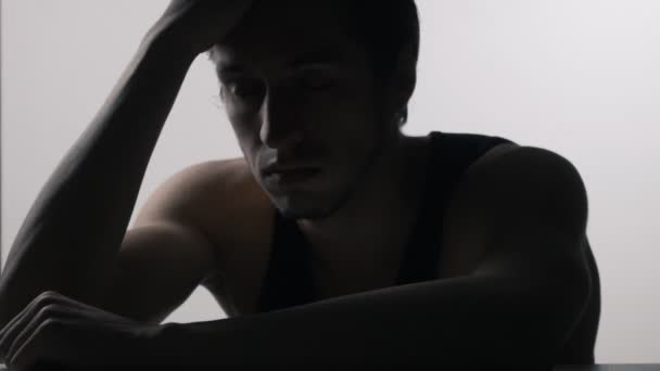 Silhouet van depressief, trieste jongeman zitten aan de tafel - Video