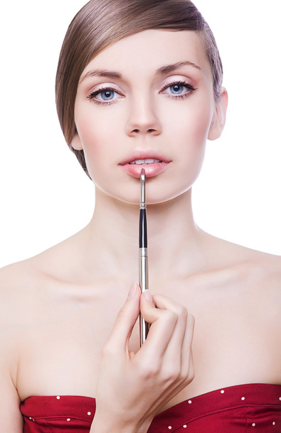 linda mujer con cepillo cosmético en los labios
 - Foto, imagen