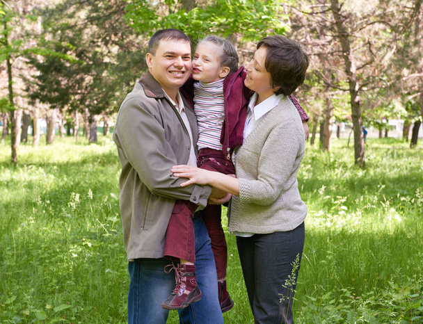 šťastná rodina a dítě v létě park, krásná krajina se stromy a zelené trávy - Fotografie, Obrázek