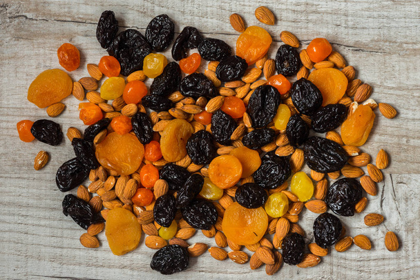 ameixas secas, damascos secos, tangerinas secas e amêndoas sobre um fundo de madeira claro
 - Foto, Imagem