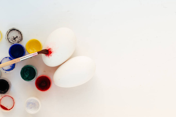 Τα αυγά, το χρώμα και το χρώμα βούρτσα πάνω στο τραπέζι. Προετοιμασία για το Πάσχα - Φωτογραφία, εικόνα