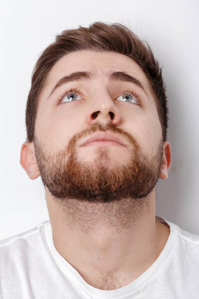 portrait of handsome young thinking man with beard looks up on w - Photo, Image