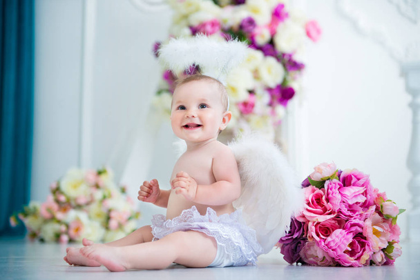 Little angel smiling and happy sitting on the background of flowers and harp - Foto, Imagen