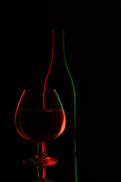 glass bottle of wine and wineglass on black background - Valokuva, kuva