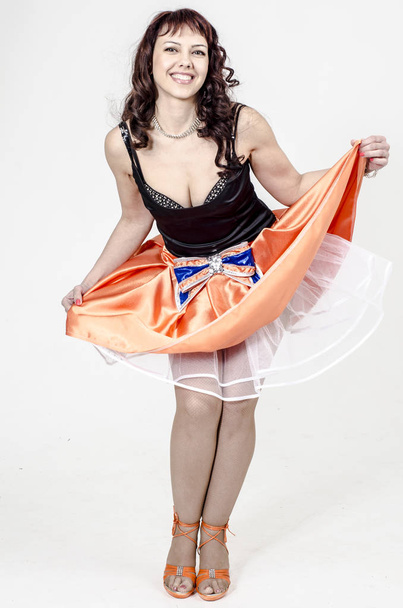 Beautiful brown-haired woman artist in chermnm corset with sequins and orange skirt with belt bow - Foto, Bild