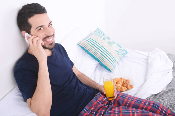 Man talking on phone in bed. - Foto, Imagen