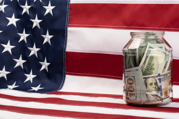 glass jar with dollars  standing on a US flag - Фото, зображення