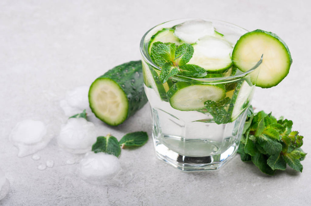 Koude en verfrissende water met komkommer en munt op grijze achtergrond. Zomer drankje komkommer limonade - Foto, afbeelding