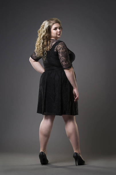 Young beautiful plus size model in black dres, xxl woman on gray studio background - Фото, зображення