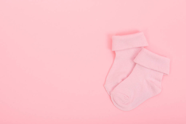 Roze babymeisje sokken op een roze achtergrond - Foto, afbeelding