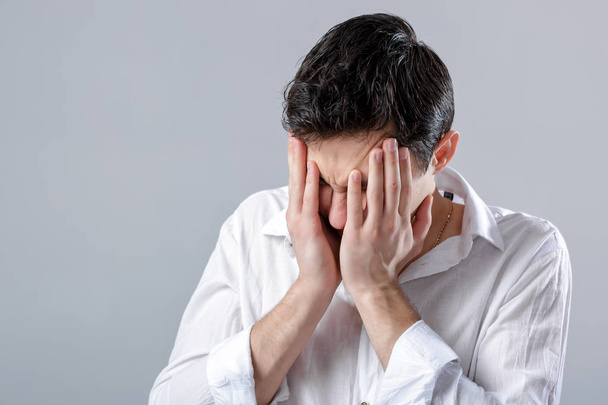 Frustrato giovane bruna uomo in camicia con mal di testa su bac grigio
 - Foto, immagini