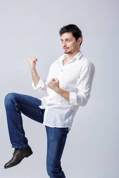 portrait of young man with dark hair in shirt raises his hands a - Фото, зображення