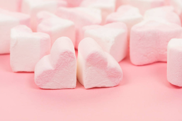 Group of heart shaped pink and white marshmallow candy on a pink background seen from the side - Фото, зображення