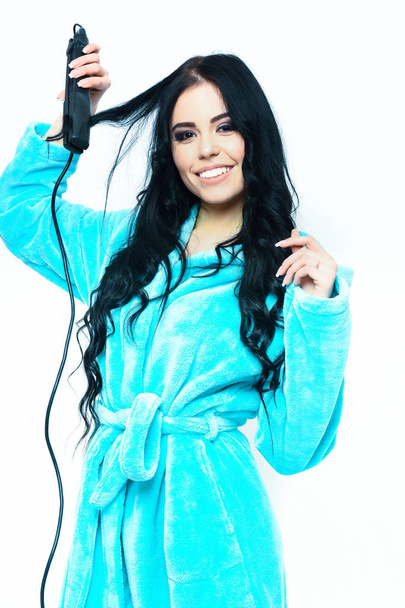 sexy girl posing in turquoise velour bathrobe with straightener - Foto, Imagem