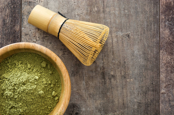 Matcha green tea in a bowl and bamboo whisk, on wooden background - Фото, изображение