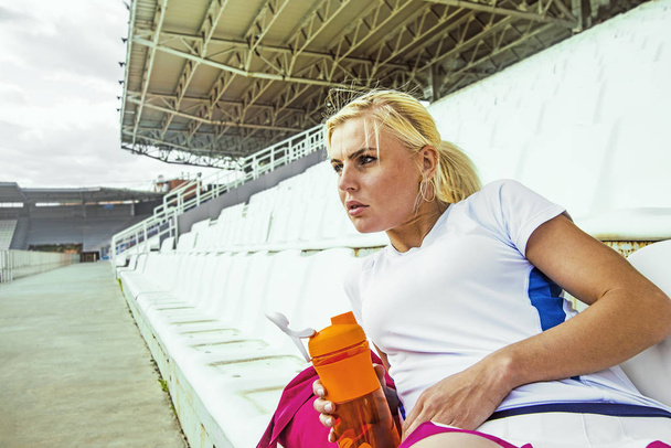 woman siting on  stadium and drinking  - Фото, зображення